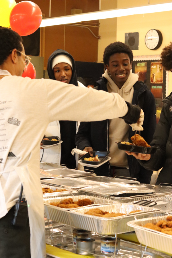 Mr. Hylton, guidance counselor, serves food to seniors Eric Roachford and Mohamed Haydara. The PaceGiving menu was catered and included fried chicken, baked potatoes, ziti pasta, and many other foods.