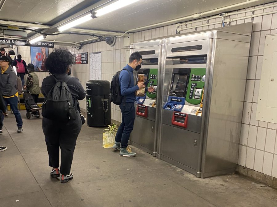 People using MTA machines in Grand Street B/D train station.