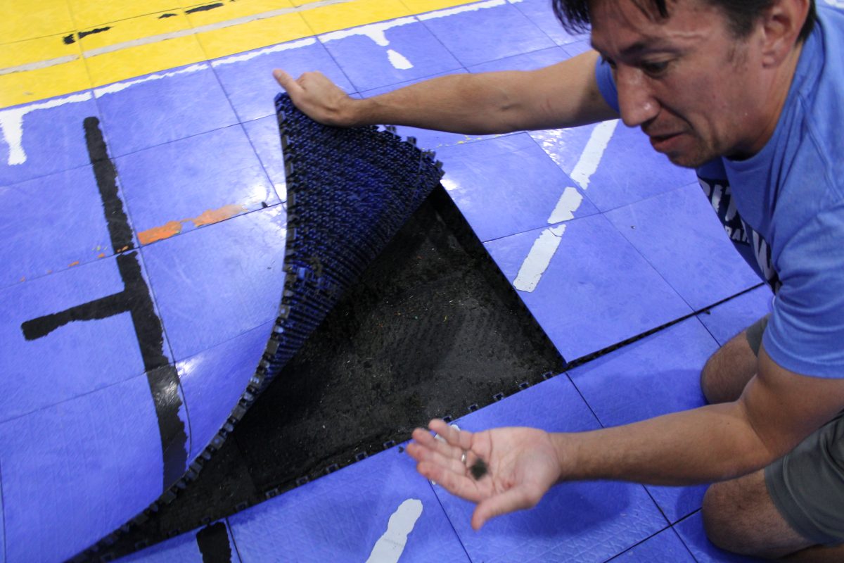 Mr. Lee lifts portion of the gyms Lego flooring, revealing the wet, black lining.