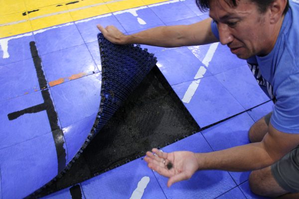 Mr. Lee lifts portion of the gyms Lego flooring, revealing the wet, black lining.