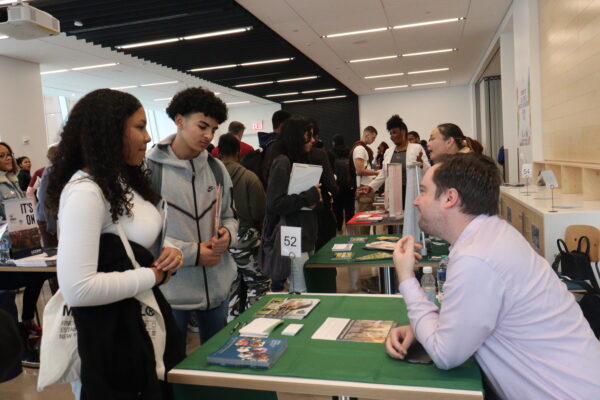 Hazem  Salem and Emma Rojas talk to a college representative at the St. Francis College Fair in Brooklyn.