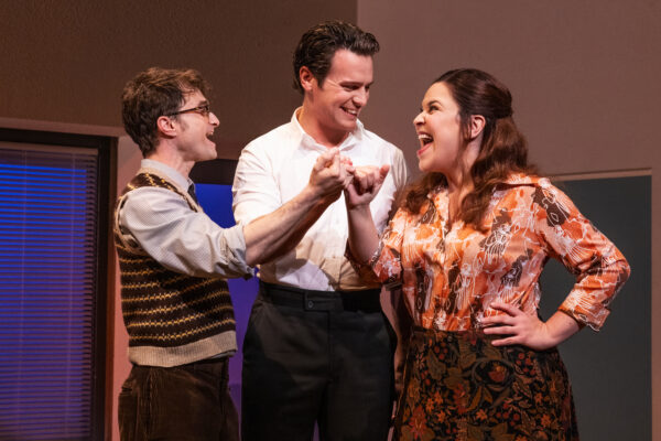 Charley Kringas, played by Daniel Radcliffe; Franklin Shepherd, played by Jonathan Groff; and Mary Flynn, played Lindsay Mendez, pinky swear to friendship with big smiles.