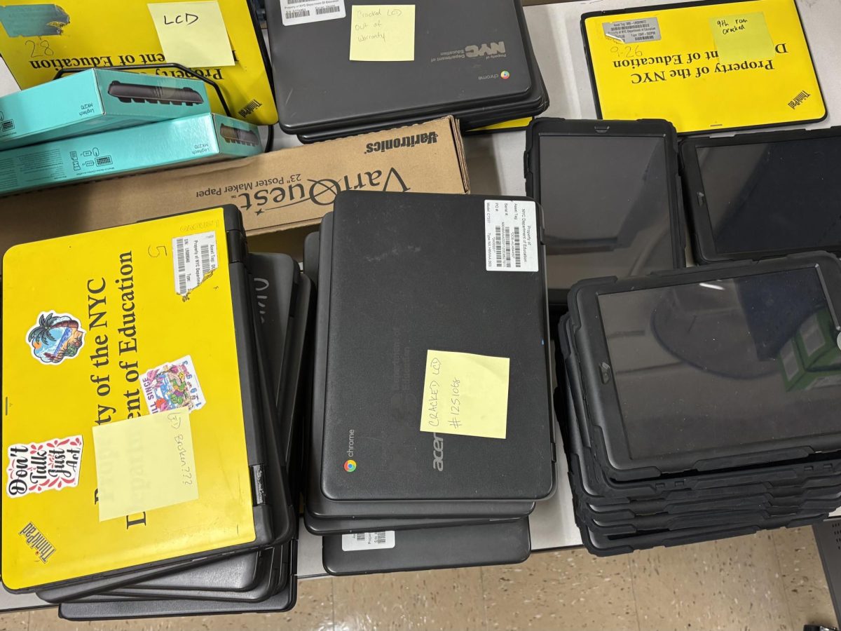 Broken school-issued laptops and iPads stacked on top of each other, ready to be replaced.
